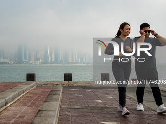 People walk along the Doha Corniche in heavy fog in Doha, Qatar, on November 6, 2024. (