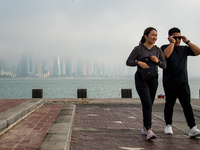 People walk along the Doha Corniche in heavy fog in Doha, Qatar, on November 6, 2024. (