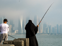 People fish at the Doha Corniche in heavy fog in Doha, Qatar, on November 6, 2024. (