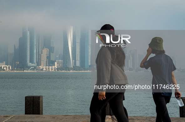 People walk along the Doha Corniche in heavy fog in Doha, Qatar, on November 6, 2024. 