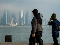 People walk along the Doha Corniche in heavy fog in Doha, Qatar, on November 6, 2024. (