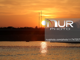 A bridge with cars is on the Vistula River at sunset in Krakow, Poland, on October 27, 2024. (