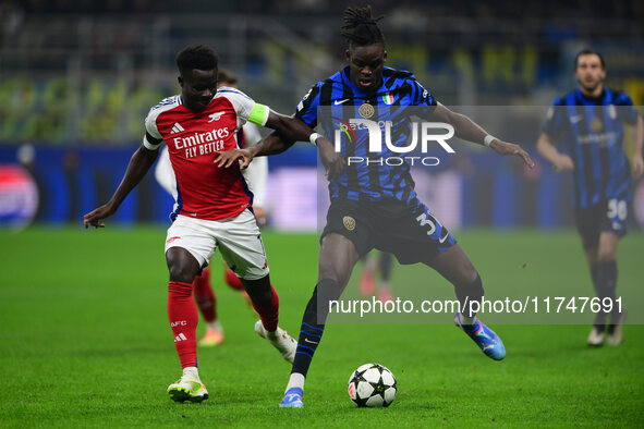 Bukayo Saka of Arsenal and Yann Aurel Bisseck of Inter Milan battle for the ball during the Champions League match between Inter Milan and A...