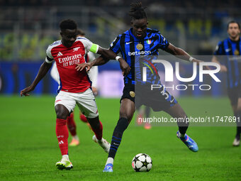 Bukayo Saka of Arsenal and Yann Aurel Bisseck of Inter Milan battle for the ball during the Champions League match between Inter Milan and A...