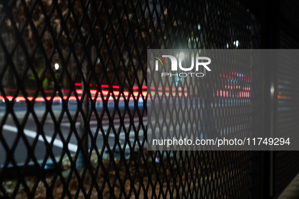 Cars pass by anti-riot fencing installed for the presidential election around the White House and Lafayette Park in Washington, DC, on Novem...