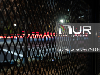 Cars pass by anti-riot fencing installed for the presidential election around the White House and Lafayette Park in Washington, DC, on Novem...