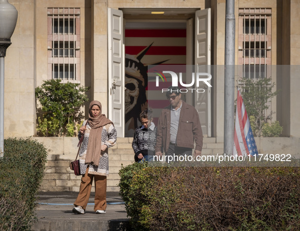 An Iranian family walks past the U.S. flag, which hangs upside down, while visiting the former U.S. embassy in Tehran, Iran, on November 7,...