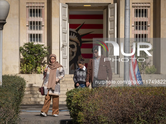 An Iranian family walks past the U.S. flag, which hangs upside down, while visiting the former U.S. embassy in Tehran, Iran, on November 7,...