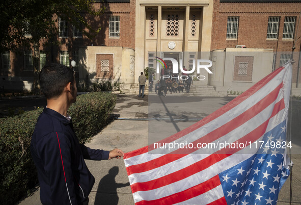 An Iranian man holds the U.S. flag, which is hung upside down, while his friends prepare to take a selfie during their visit to the former U...