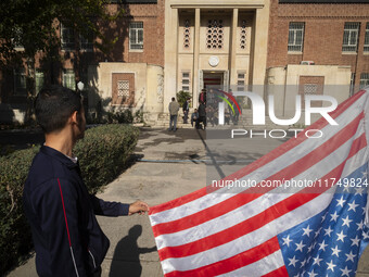 An Iranian man holds the U.S. flag, which is hung upside down, while his friends prepare to take a selfie during their visit to the former U...