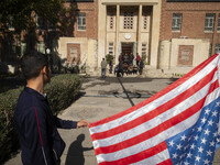 An Iranian man holds the U.S. flag, which is hung upside down, while his friends prepare to take a selfie during their visit to the former U...