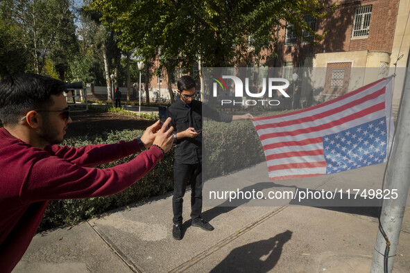 An Iranian man holds the U.S. flag, which hangs upside down, while his friend takes photographs during their visit to the former U.S. embass...