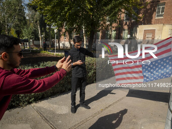 An Iranian man holds the U.S. flag, which hangs upside down, while his friend takes photographs during their visit to the former U.S. embass...