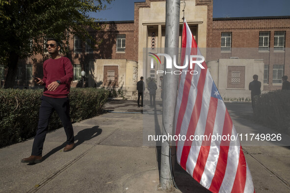 An Iranian man walks past the U.S. flag, which hangs upside down, while visiting the former U.S. embassy in Tehran, Iran, on November 7, 202...