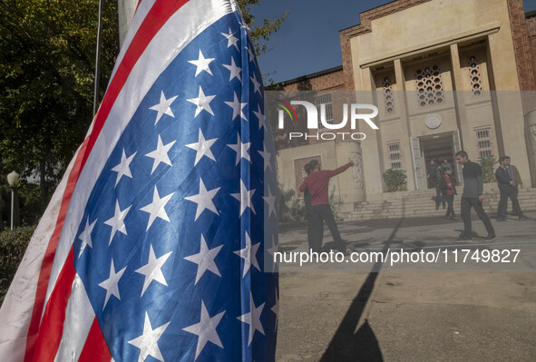 Two Iranian men take a selfie while standing next to the U.S. flag, which hangs upside down at the former U.S. embassy in Tehran, Iran, on N...