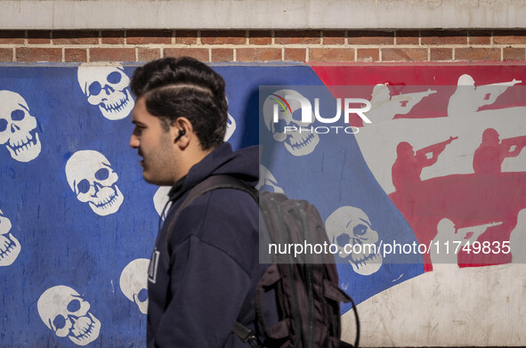 A young Iranian man walks past an anti-U.S. mural on a wall of the former U.S. embassy in Tehran, Iran, on November 7, 2024. Former U.S. Pre...