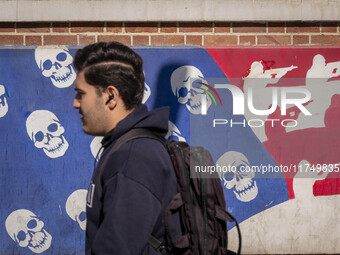 A young Iranian man walks past an anti-U.S. mural on a wall of the former U.S. embassy in Tehran, Iran, on November 7, 2024. Former U.S. Pre...