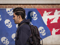 A young Iranian man walks past an anti-U.S. mural on a wall of the former U.S. embassy in Tehran, Iran, on November 7, 2024. Former U.S. Pre...