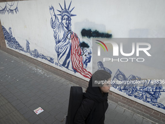 A young Iranian woman walks past an anti-U.S. mural on a wall of the former U.S. embassy in Tehran, Iran, on November 7, 2024. Former U.S. P...