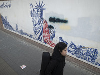 A young Iranian woman walks past an anti-U.S. mural on a wall of the former U.S. embassy in Tehran, Iran, on November 7, 2024. Former U.S. P...