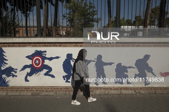 A young Iranian woman walks past an anti-U.S. mural on a wall of the former U.S. embassy in Tehran, Iran, on November 7, 2024. Former U.S. P...