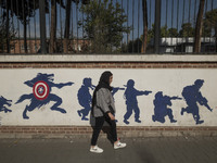 A young Iranian woman walks past an anti-U.S. mural on a wall of the former U.S. embassy in Tehran, Iran, on November 7, 2024. Former U.S. P...