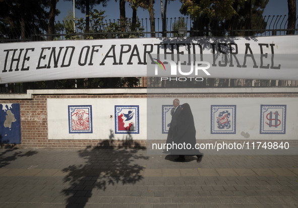 An elderly Iranian couple walks past an anti-U.S. mural on a wall of the former U.S. embassy in Tehran, Iran, on November 7, 2024. Former U....