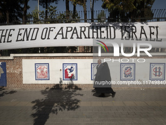 An elderly Iranian couple walks past an anti-U.S. mural on a wall of the former U.S. embassy in Tehran, Iran, on November 7, 2024. Former U....