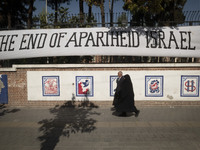 An elderly Iranian couple walks past an anti-U.S. mural on a wall of the former U.S. embassy in Tehran, Iran, on November 7, 2024. Former U....