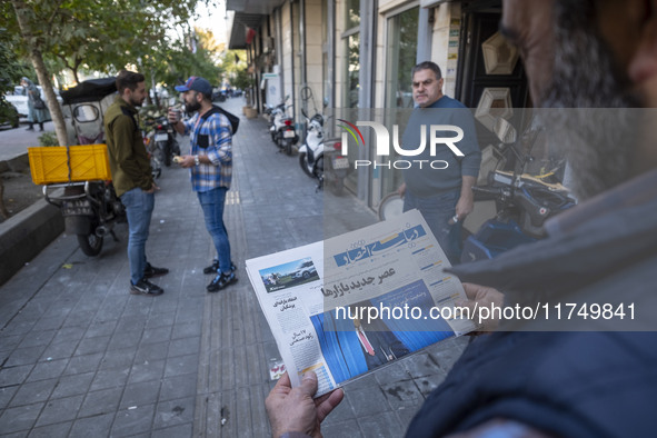 An Iranian man reads a newspaper with an image of the U.S. President-elect, Donald Trump, on its front page while standing on a sidewalk in...