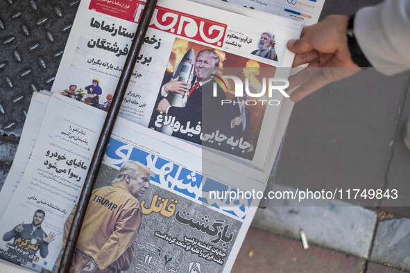 An Iranian man picks up a newspaper with an image of the U.S. President-elect, Donald Trump, published on its front page in downtown Tehran,...