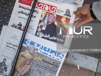 An Iranian man picks up a newspaper with an image of the U.S. President-elect, Donald Trump, published on its front page in downtown Tehran,...