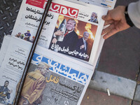 An Iranian man picks up a newspaper with an image of the U.S. President-elect, Donald Trump, published on its front page in downtown Tehran,...