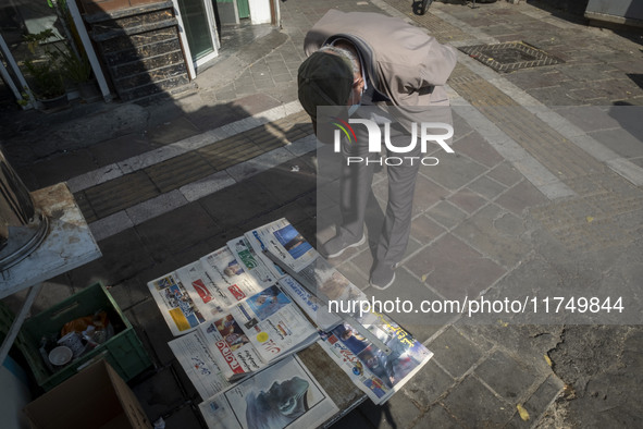 An elderly Iranian man reads newspapers with images of the U.S. President-elect, Donald Trump, on their front pages on a sidewalk in downtow...