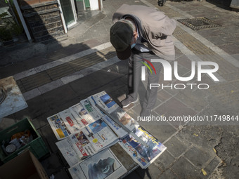 An elderly Iranian man reads newspapers with images of the U.S. President-elect, Donald Trump, on their front pages on a sidewalk in downtow...