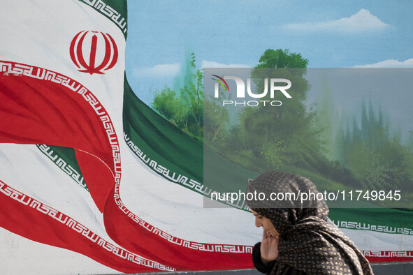 An Iranian woman walks past a mural featuring an Iranian flag in downtown Tehran, Iran, on November 7, 2024. Former U.S. President and Repub...