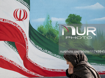 An Iranian woman walks past a mural featuring an Iranian flag in downtown Tehran, Iran, on November 7, 2024. Former U.S. President and Repub...