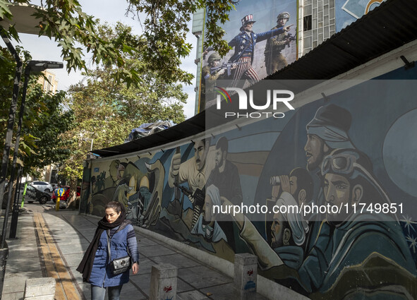 A young Iranian woman walks past an anti-U.S. banner and an anti-Israeli mural in downtown Tehran, Iran, on November 7, 2024. Former U.S. Pr...