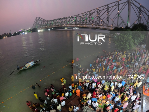 A Hindu devotee offers prayers to the sun god during the Chhath Festival at the Ganga ghat and the backside of Howrah Bridge in Kolkata, Ind...