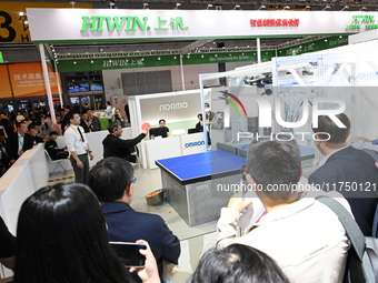 Visitors experience Omron's 9th generation table tennis coaching robot at the Technical equipment exhibition area of the 7th China Internati...