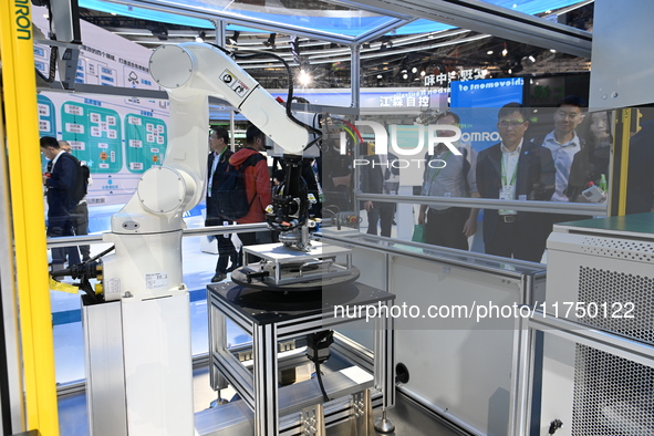 Visitors experience Omron's 9th generation table tennis coaching robot at the Technical equipment exhibition area of the 7th China Internati...