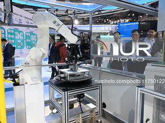 Visitors experience Omron's 9th generation table tennis coaching robot at the Technical equipment exhibition area of the 7th China Internati...