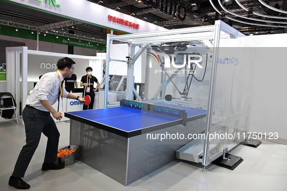 Visitors experience Omron's 9th generation table tennis coaching robot at the Technical equipment exhibition area of the 7th China Internati...