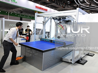 Visitors experience Omron's 9th generation table tennis coaching robot at the Technical equipment exhibition area of the 7th China Internati...