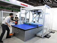 Visitors experience Omron's 9th generation table tennis coaching robot at the Technical equipment exhibition area of the 7th China Internati...