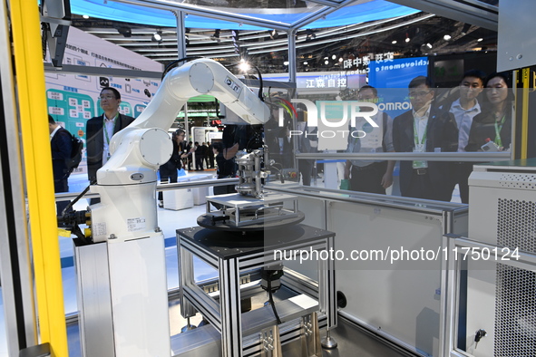 Visitors experience Omron's 9th generation table tennis coaching robot at the Technical equipment exhibition area of the 7th China Internati...