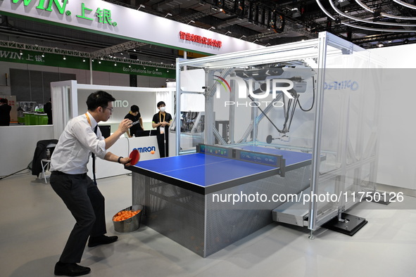 Visitors experience Omron's 9th generation table tennis coaching robot at the Technical equipment exhibition area of the 7th China Internati...