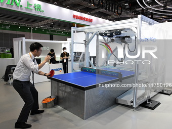 Visitors experience Omron's 9th generation table tennis coaching robot at the Technical equipment exhibition area of the 7th China Internati...