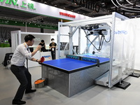 Visitors experience Omron's 9th generation table tennis coaching robot at the Technical equipment exhibition area of the 7th China Internati...