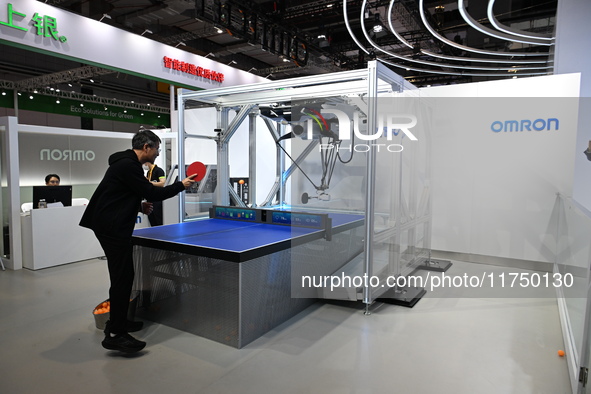 Visitors experience Omron's 9th generation table tennis coaching robot at the Technical equipment exhibition area of the 7th China Internati...